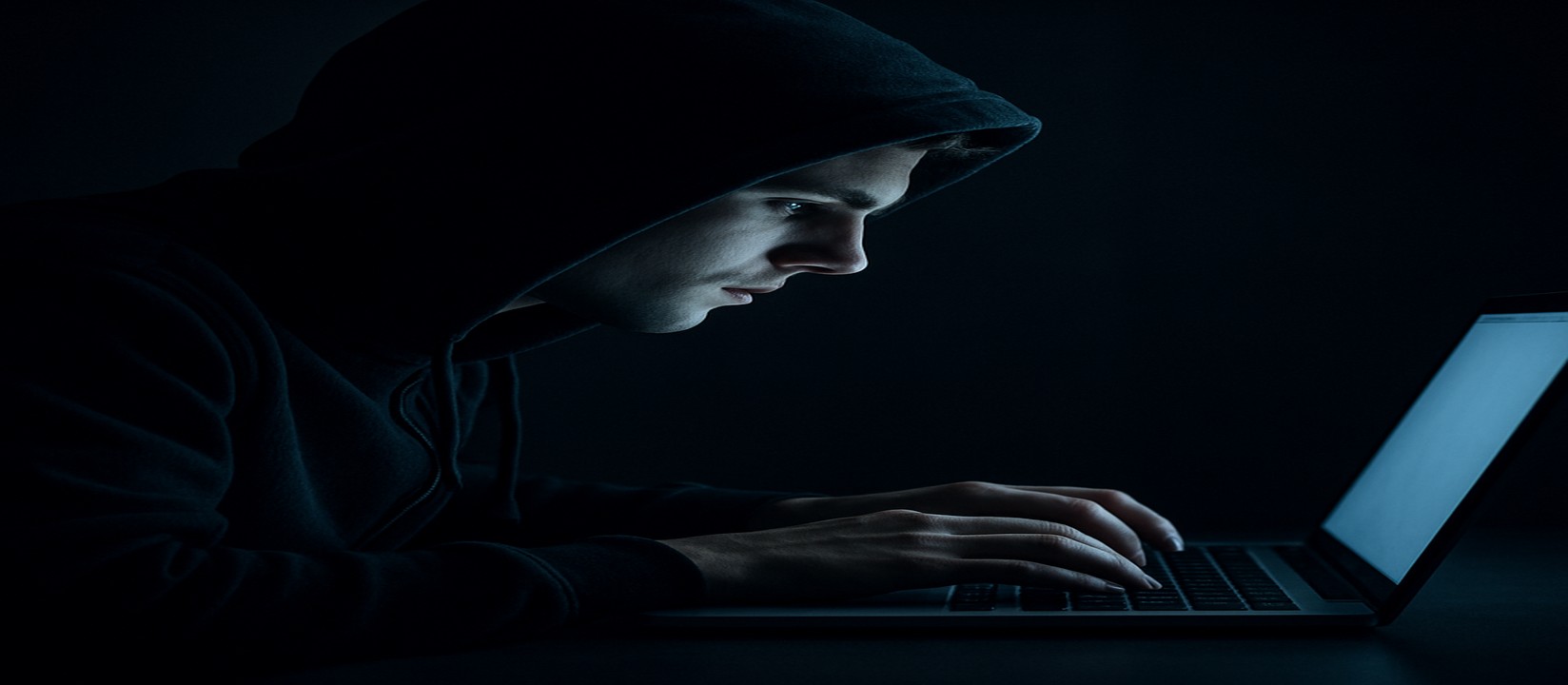 একজন ব্যক্তি অন্ধকার ঘরে ল্যাপটপের সামনে মনোযোগ সহকারে 3777bdt ওয়েবসাইটে অনলাইন গেমিং করছেন